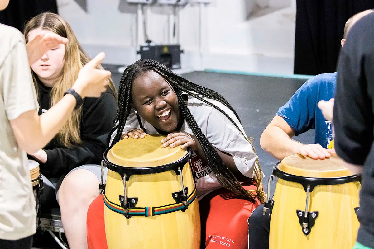 A smiling girl trying her hand at the drums