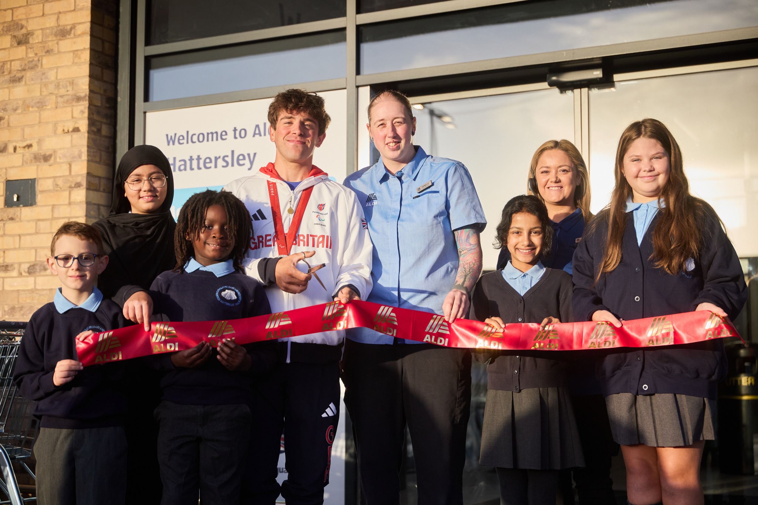 Paralympian Archie Atkinson, store manager Danielle Airey and children from St James' Primary cut the ribbon